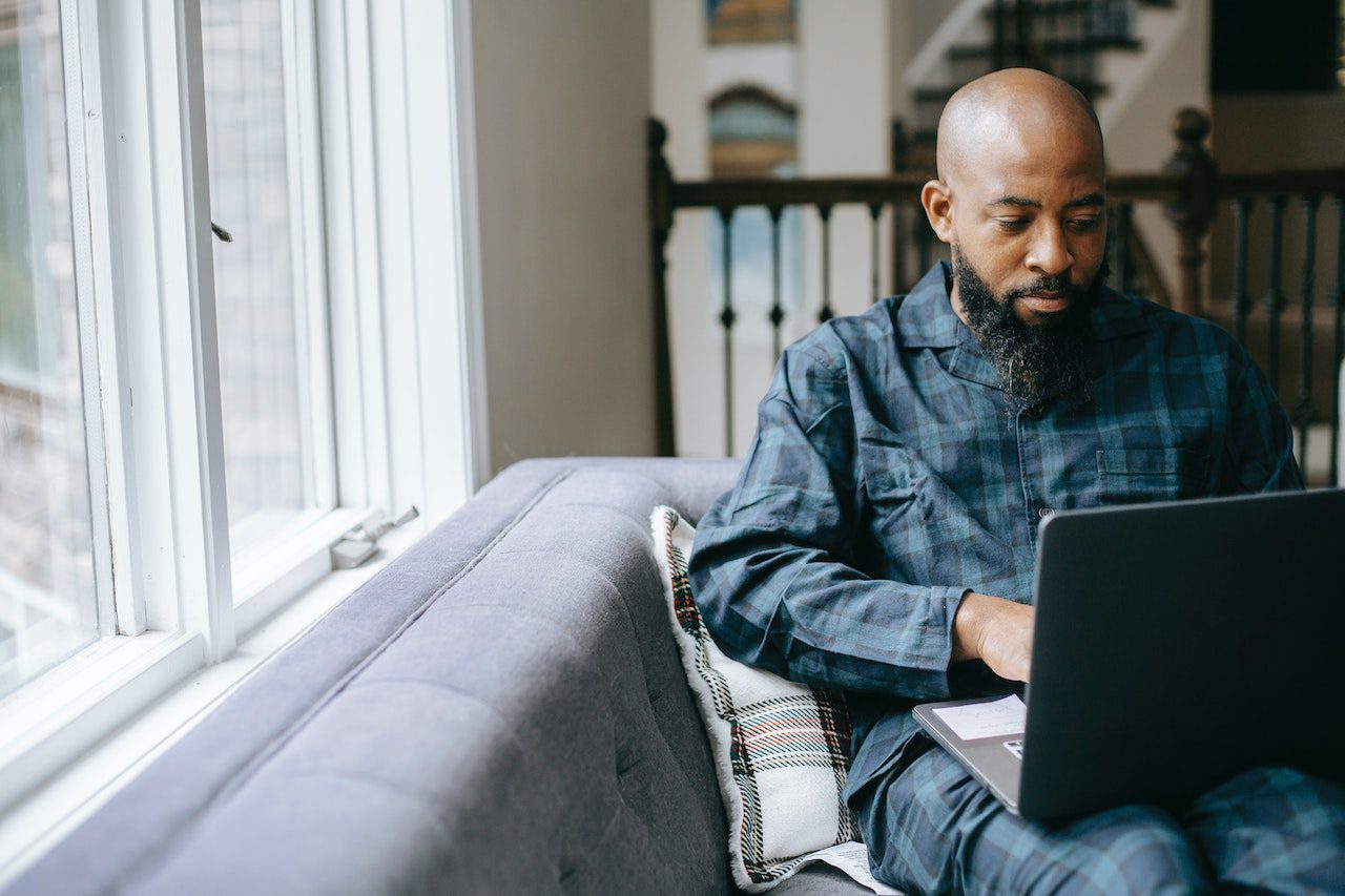 Man editing a video on his laptop while sitting on a couch